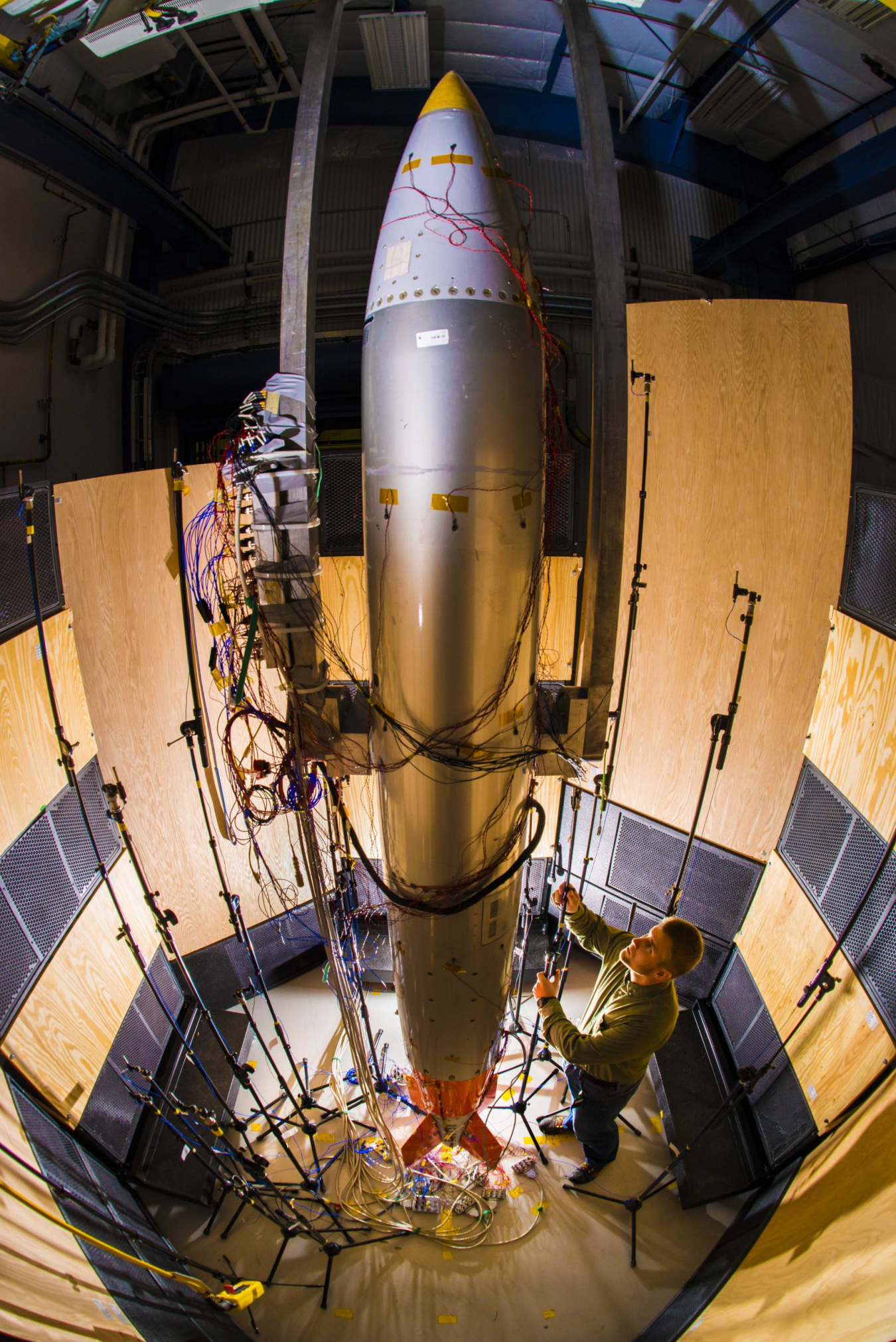 A worker at Sandia National Labs adjusts a microphone for an acoustics test on a B61-12 system .