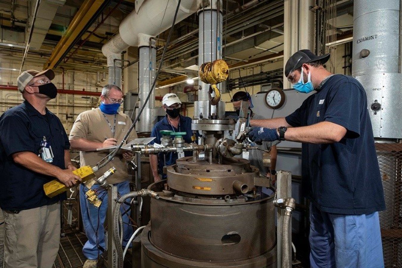 Workers at Y-12 working on heavy machinery