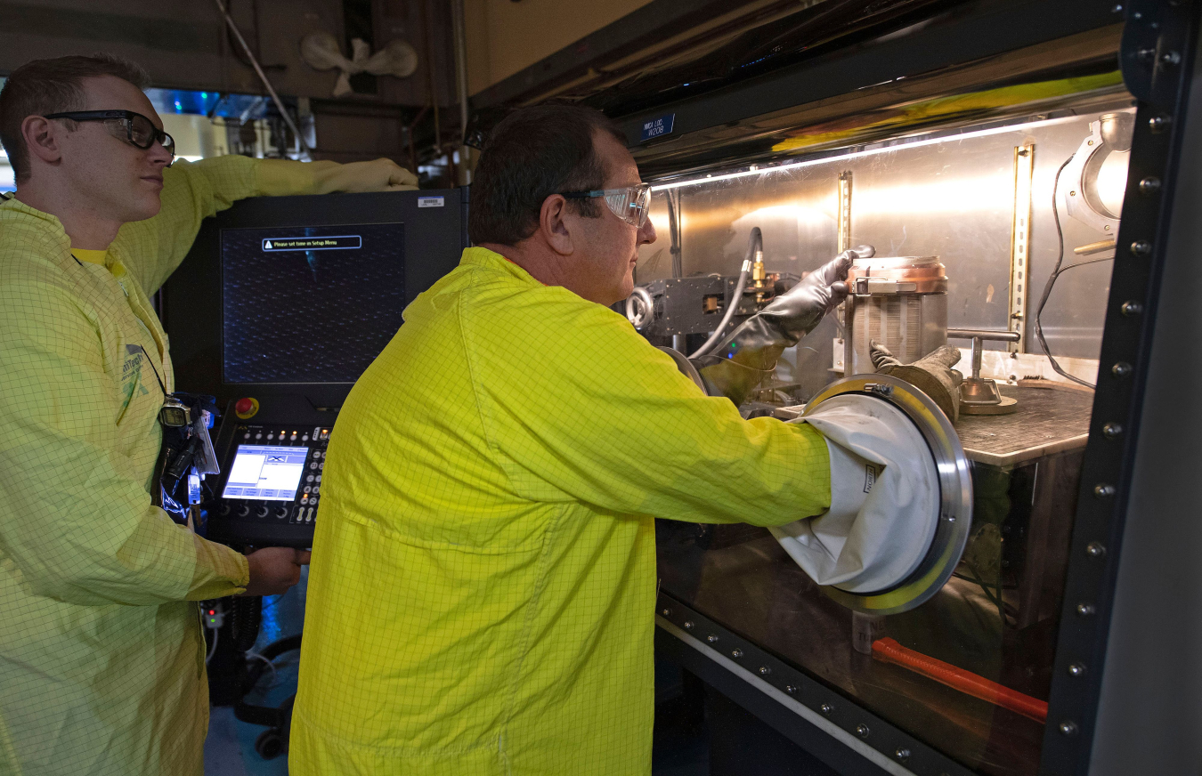 Lab workers working in a glovebox.