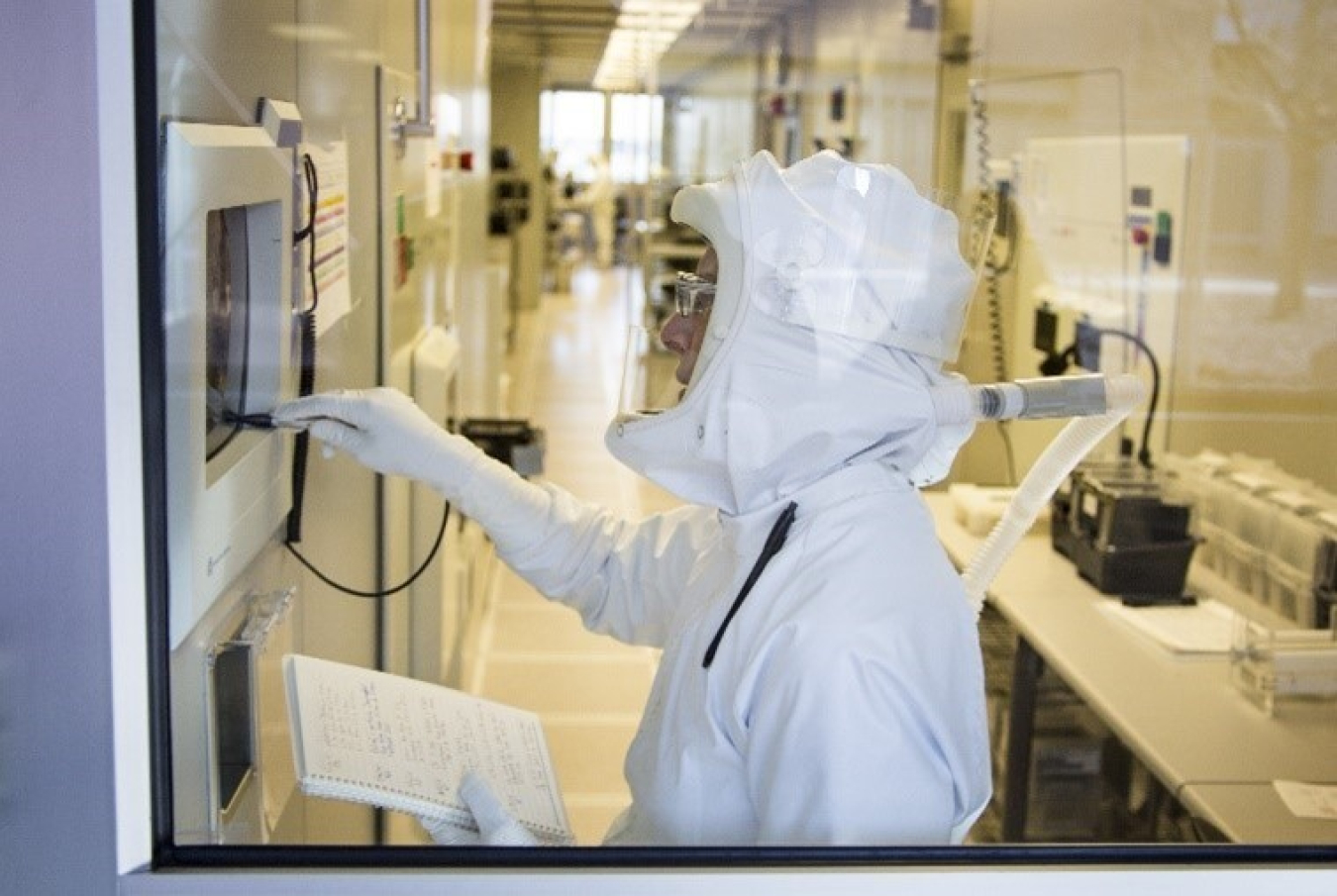 Scientist in a safety suit taking notes.