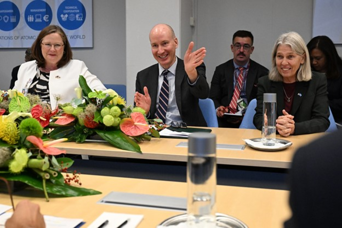 Ambassador Laura Holgate, Deputy Secretary David Turk, and NNSA Administrator Jill Hruby sit at a table. Everyone is smiling and Turk is gesturing.