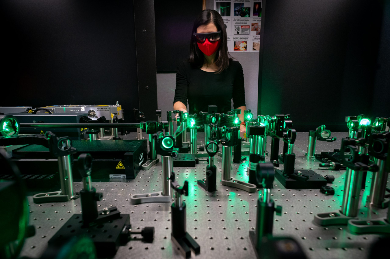 An Image of a woman standing behind a table. On the table there are laser instruments.