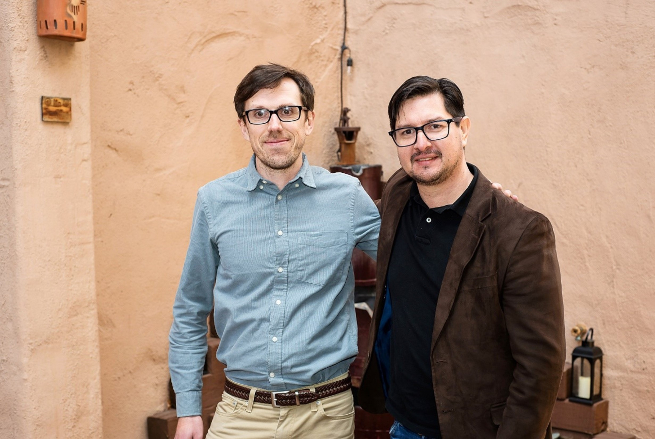 Two men standing and smiling. 