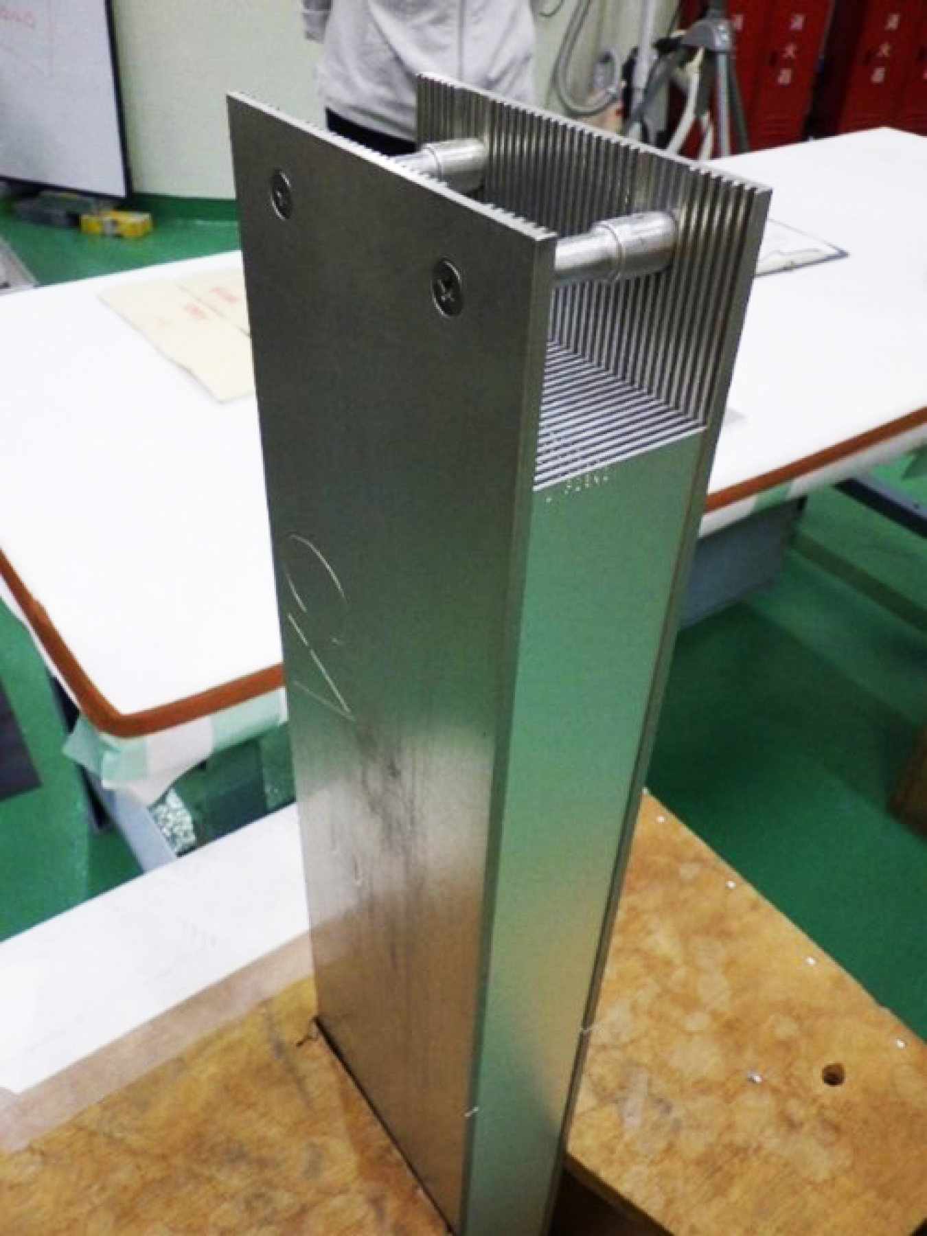 A metal object about 8 inches by 3 inches by 3 feet in size sits on a table.