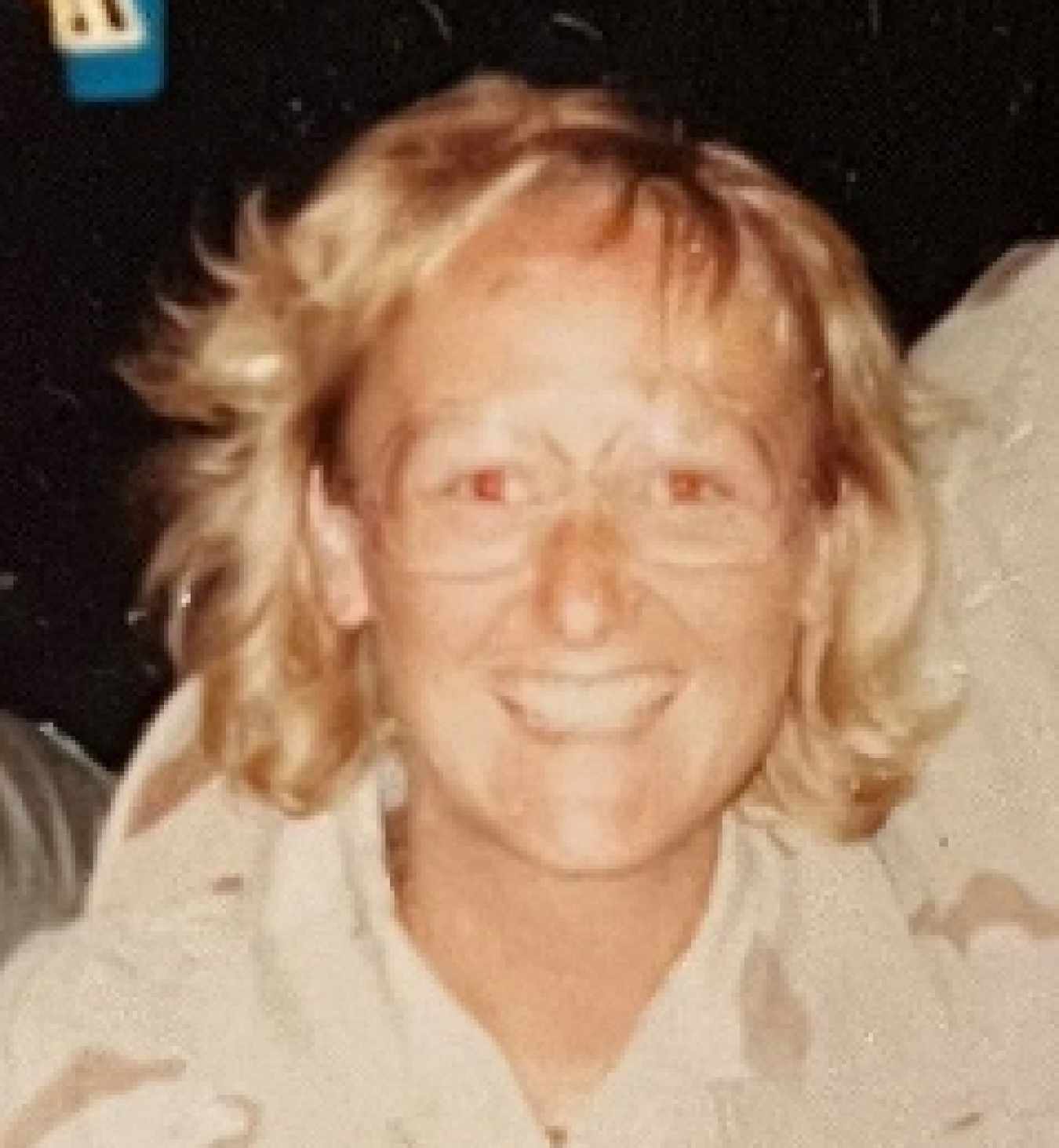 A woman with short, blonde hair and glasses smiles for a picture while wearing a military uniform