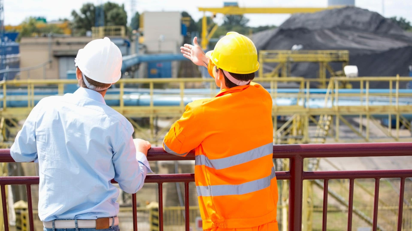 Two workers looking at a building site.