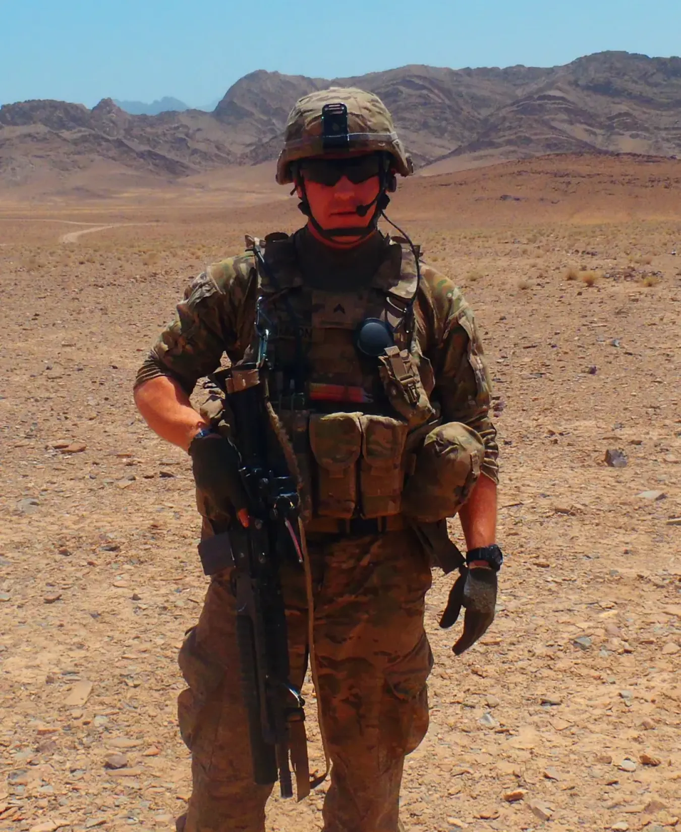 A military person in uniform in a desert.