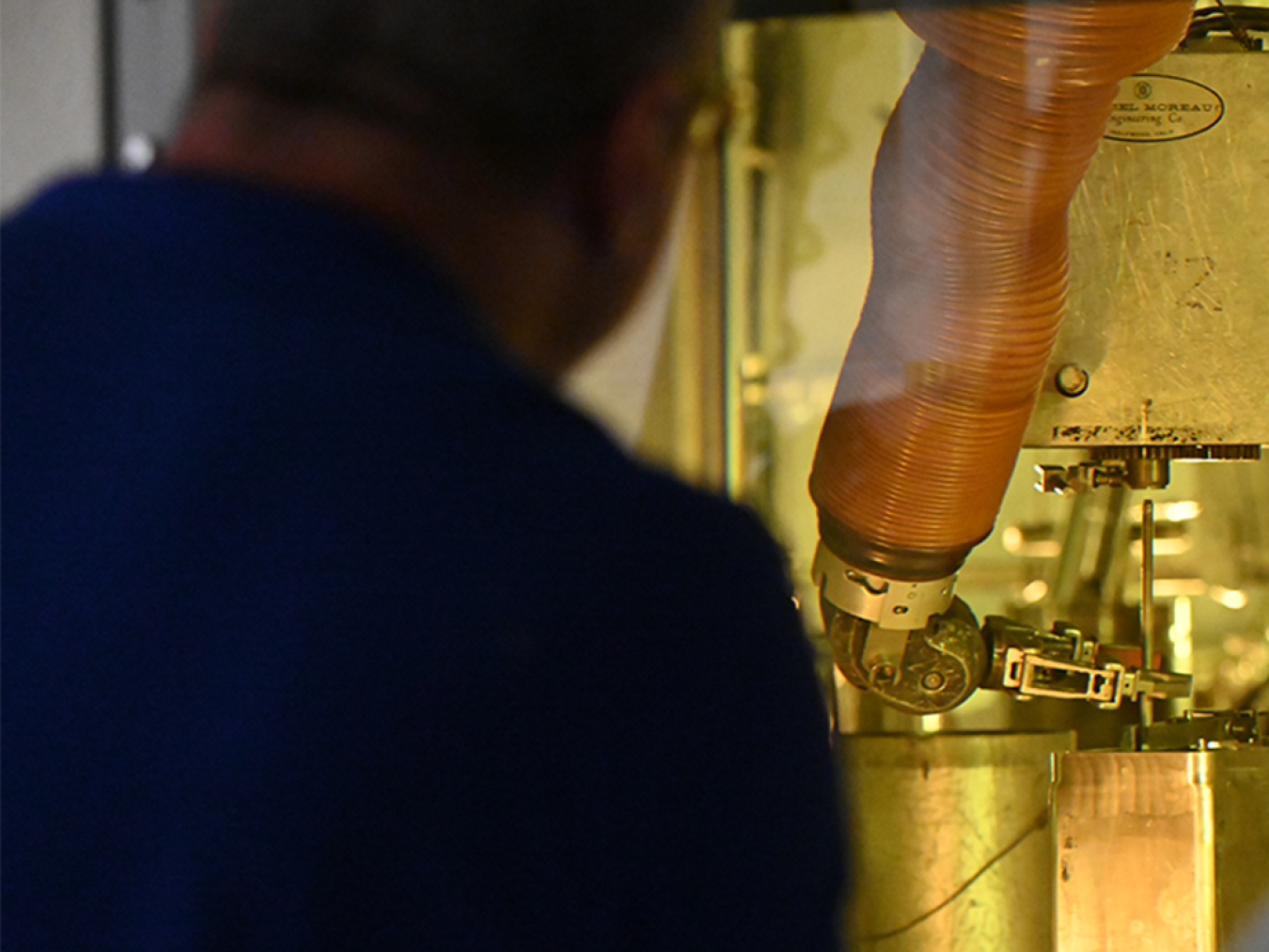 Researcher looking through the glass of a hot cell at a spent fuel rod.