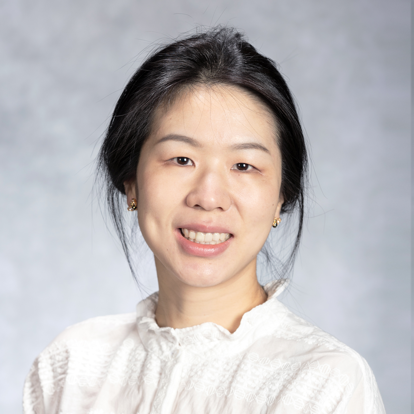 A woman smiling with her hair tied back