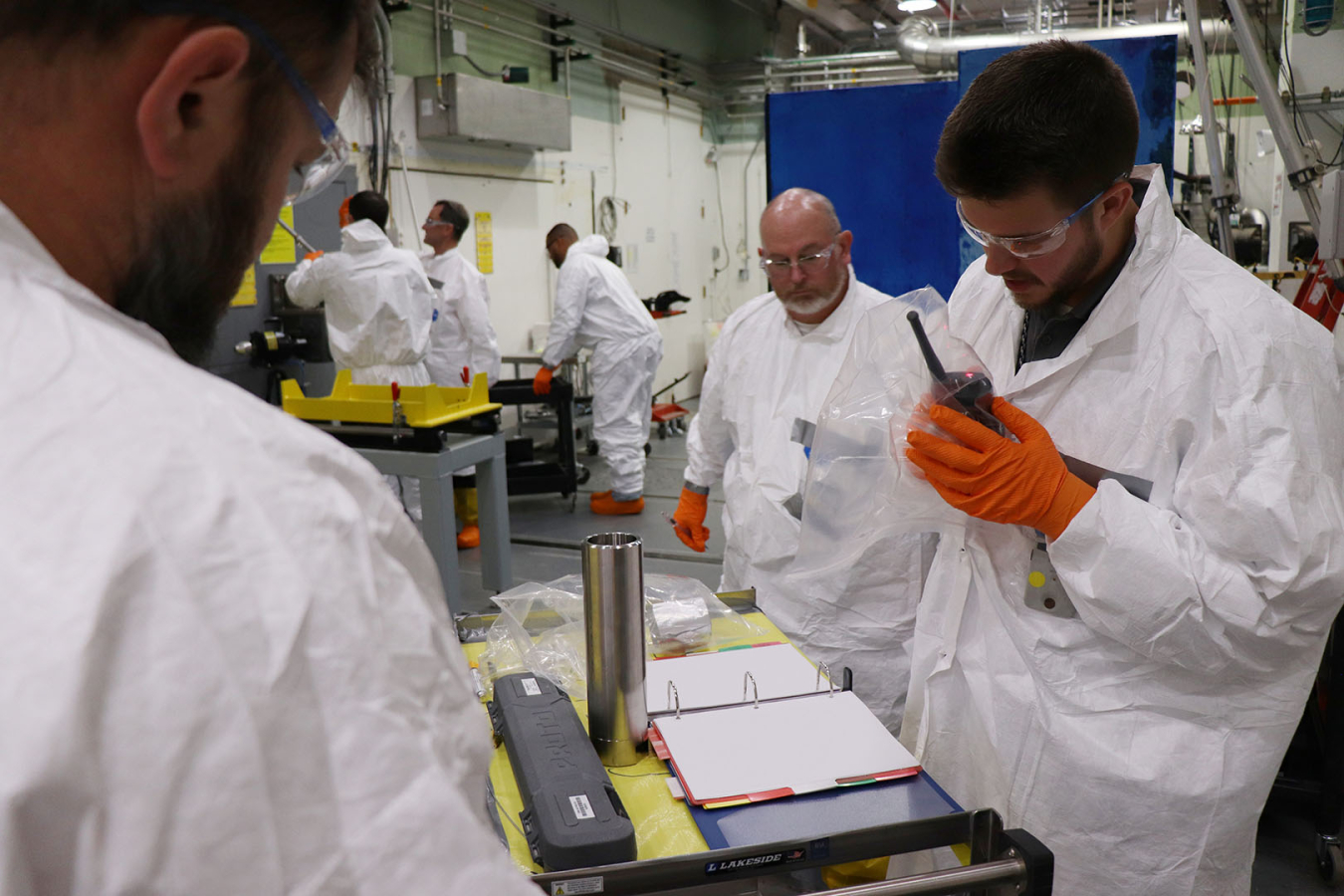 Three employees in white protective suits