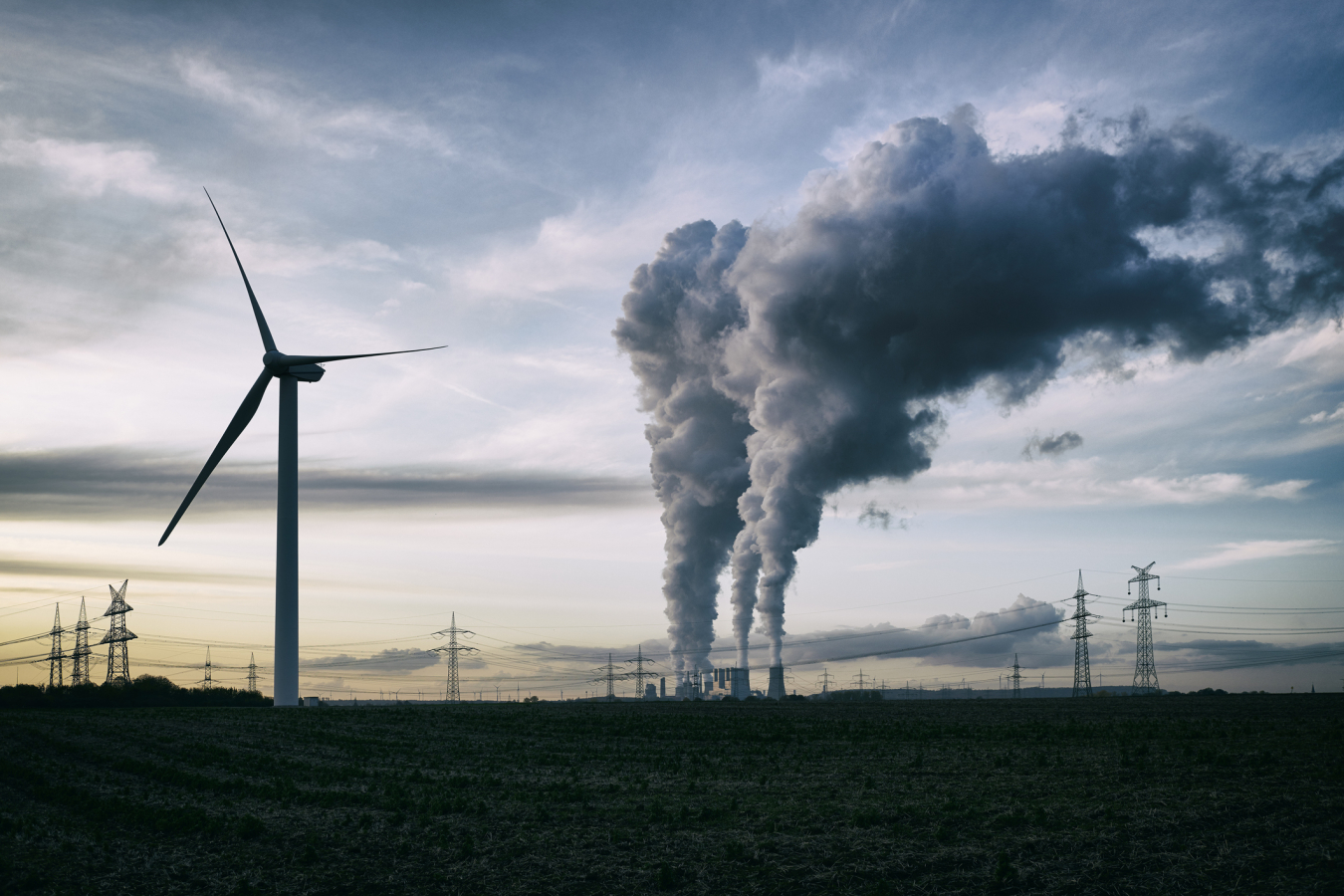 Wind turbine and billowing smoke from a factory.