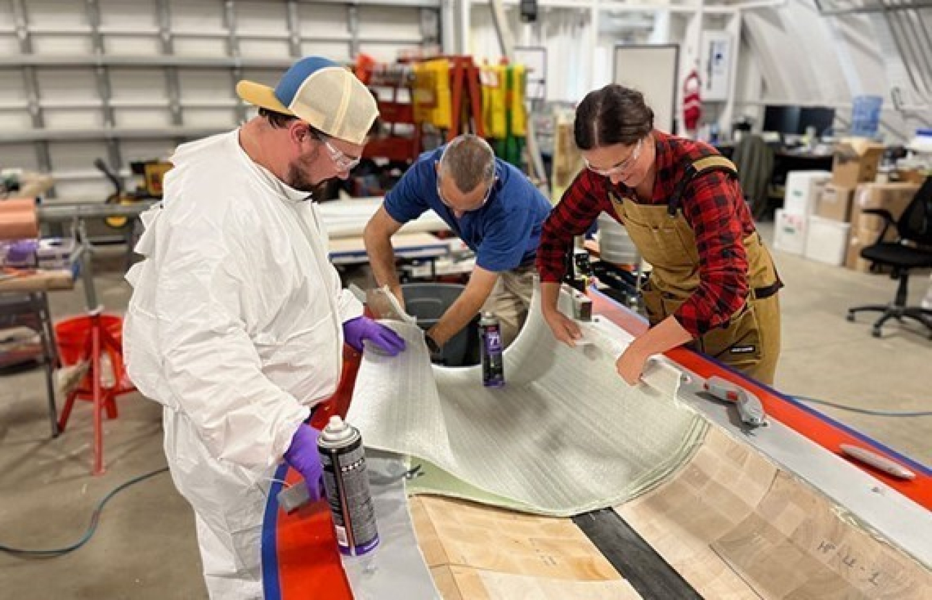 People in lab attire work on a mold of a wind turbine