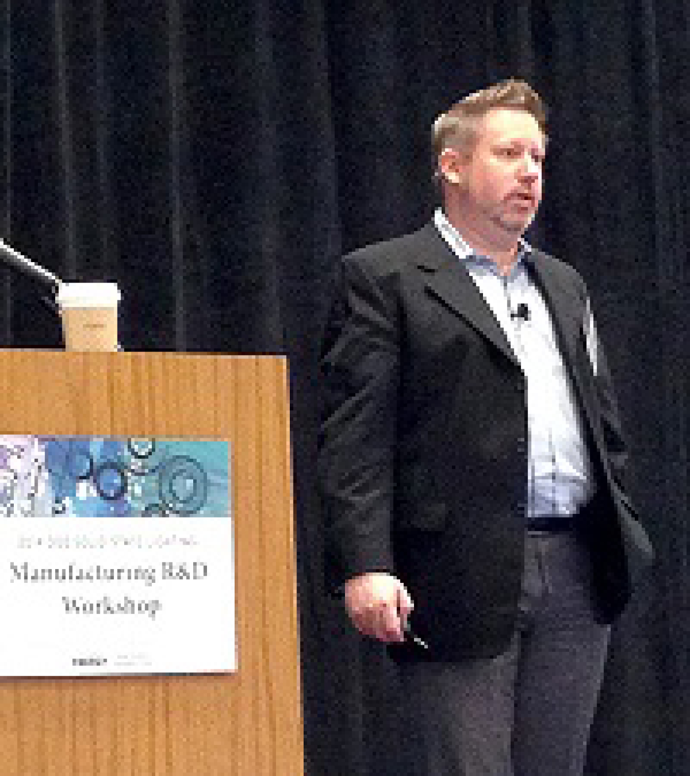 Man standing next to a lectern addressing an audience at an event.