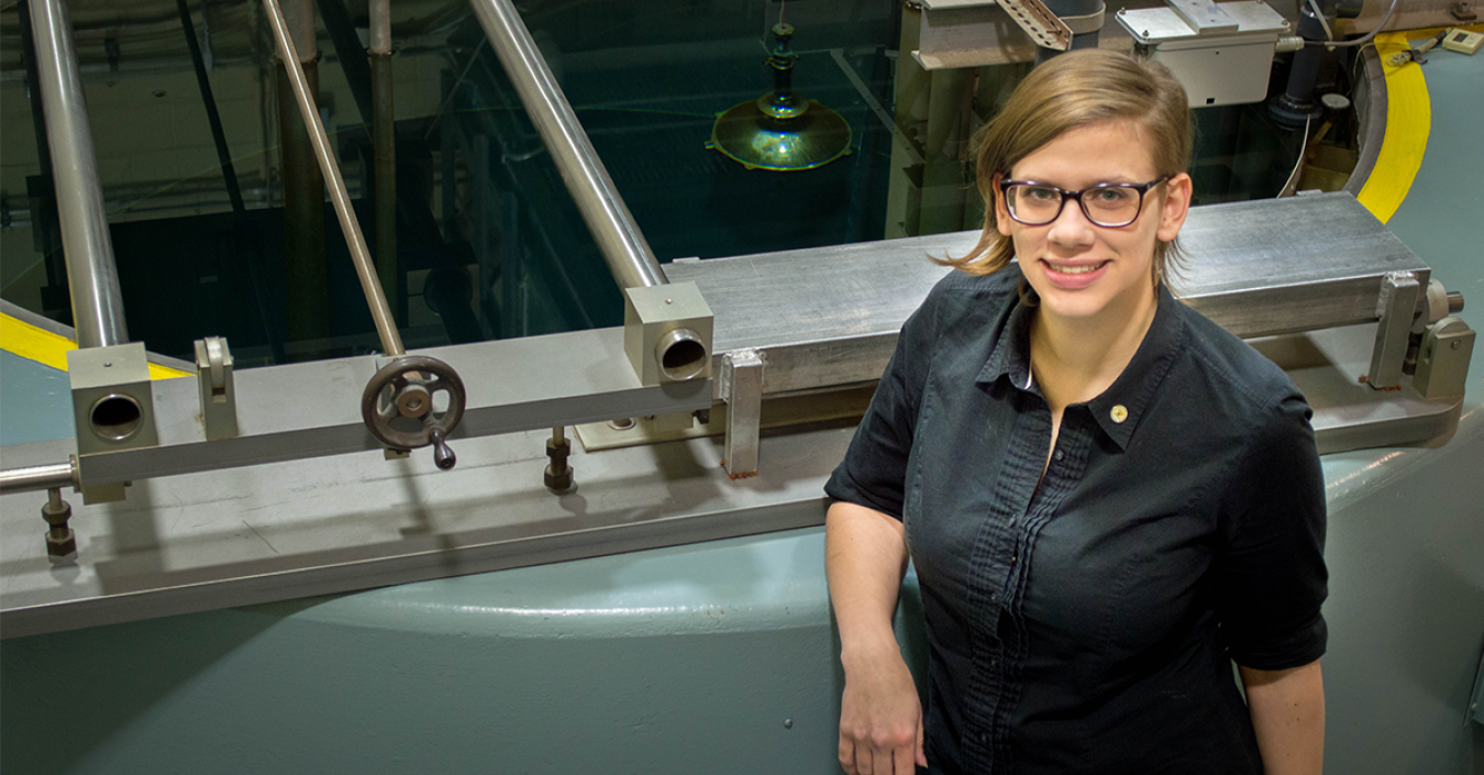 A woman poses in front of a research reactor.