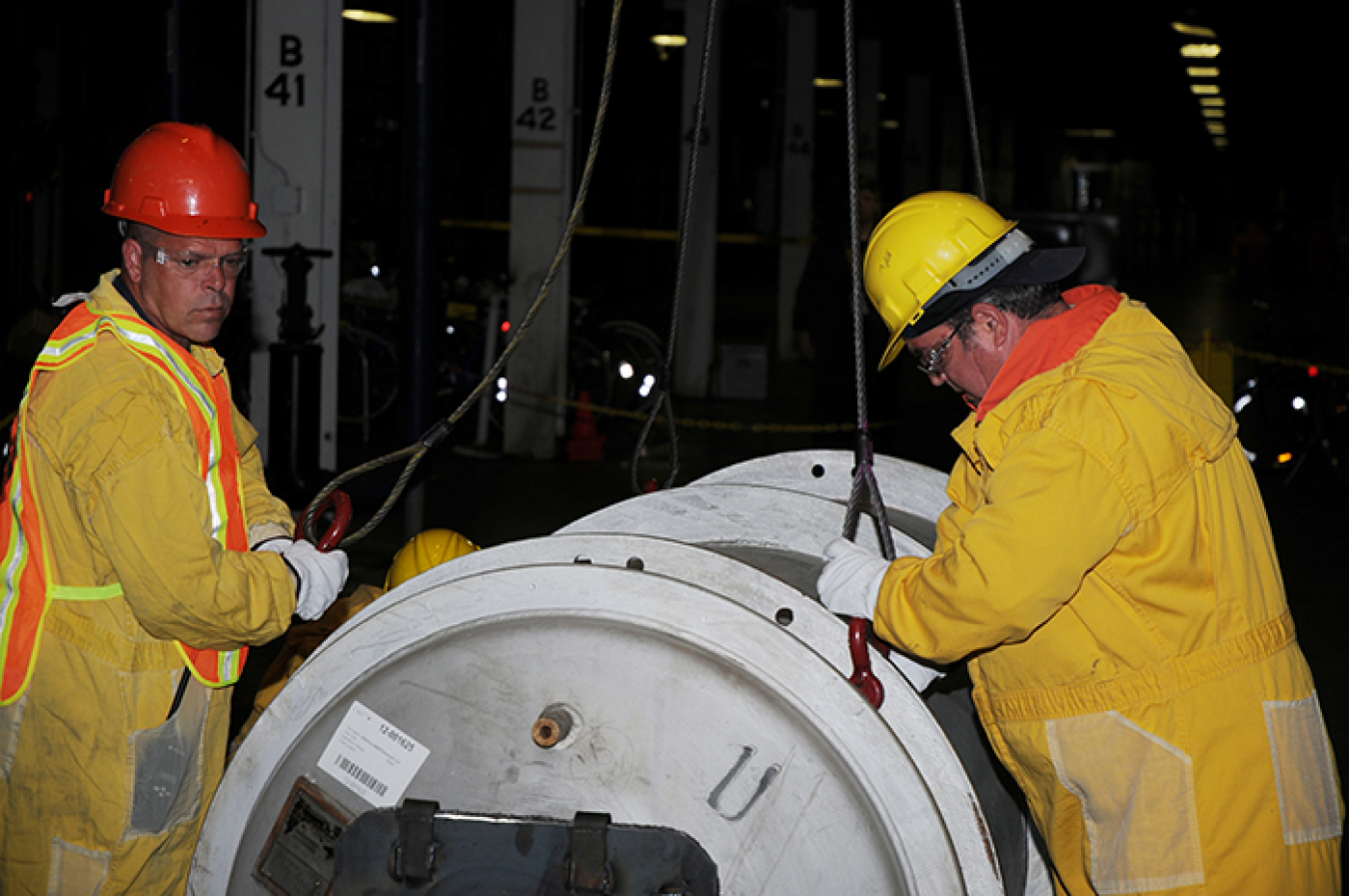 Workers in the X-326 building package a component.