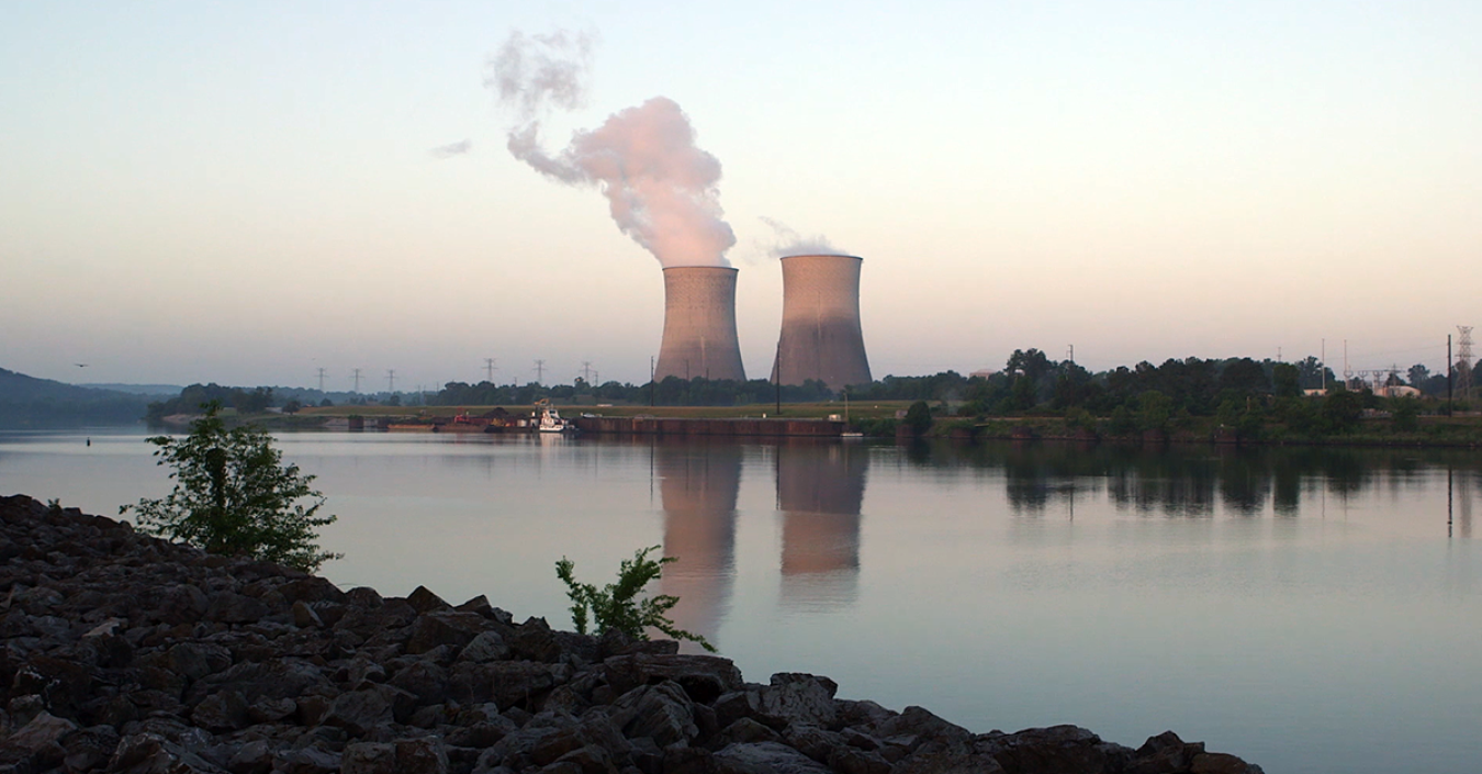 A photo of two cooling stacks in the distance with a river in the foreground