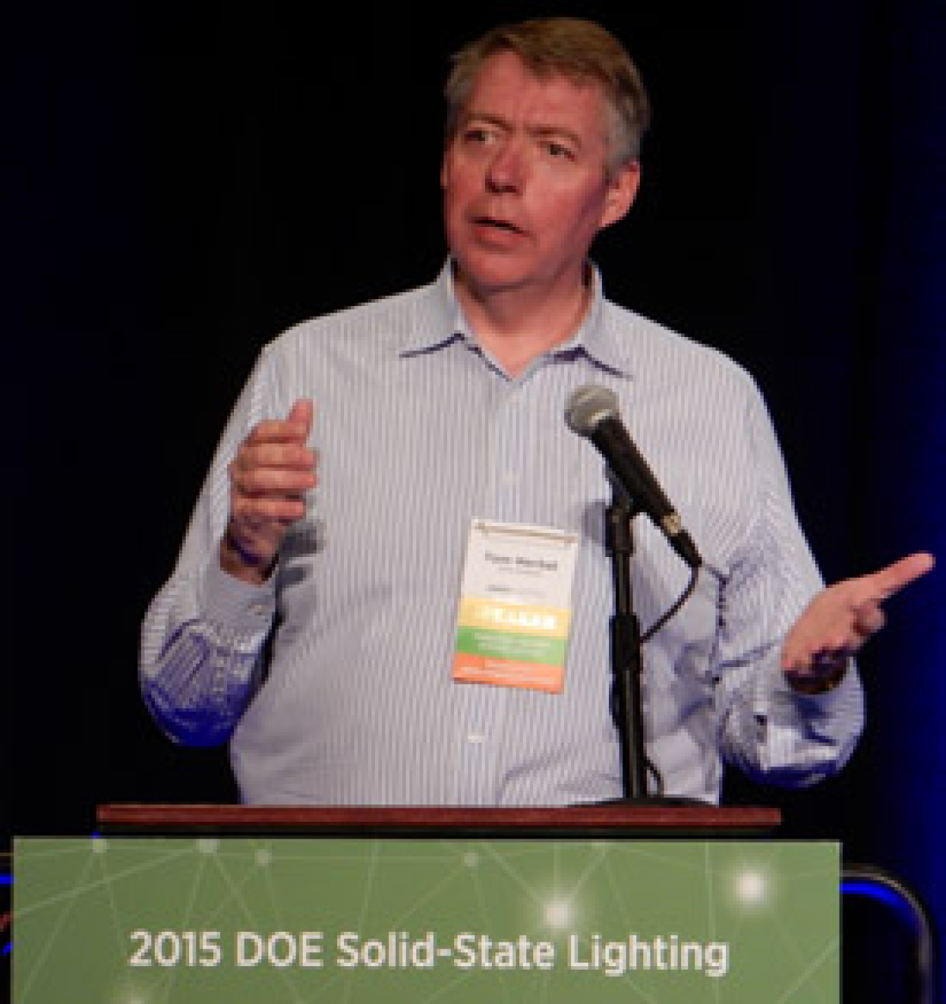 Man standing at a lectern addressing an audience.