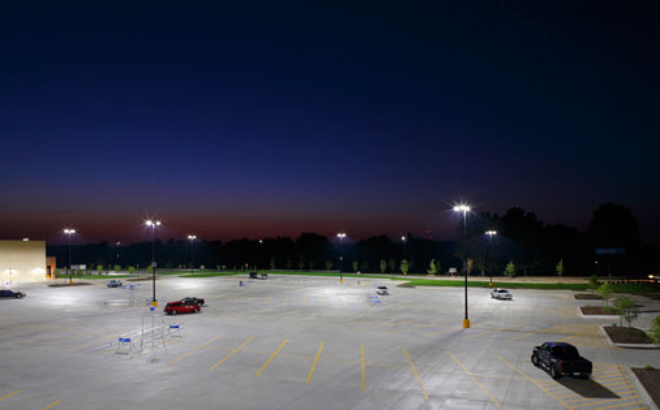 Photo of a parking lot at night with lights on.