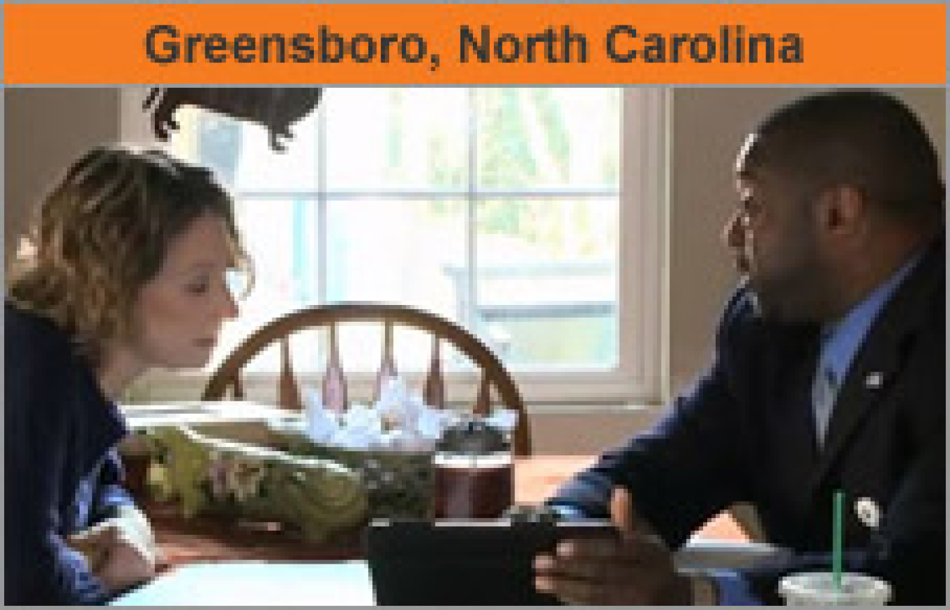 A man and a woman talking at a table, with the words "Greensboro, North Carolina."