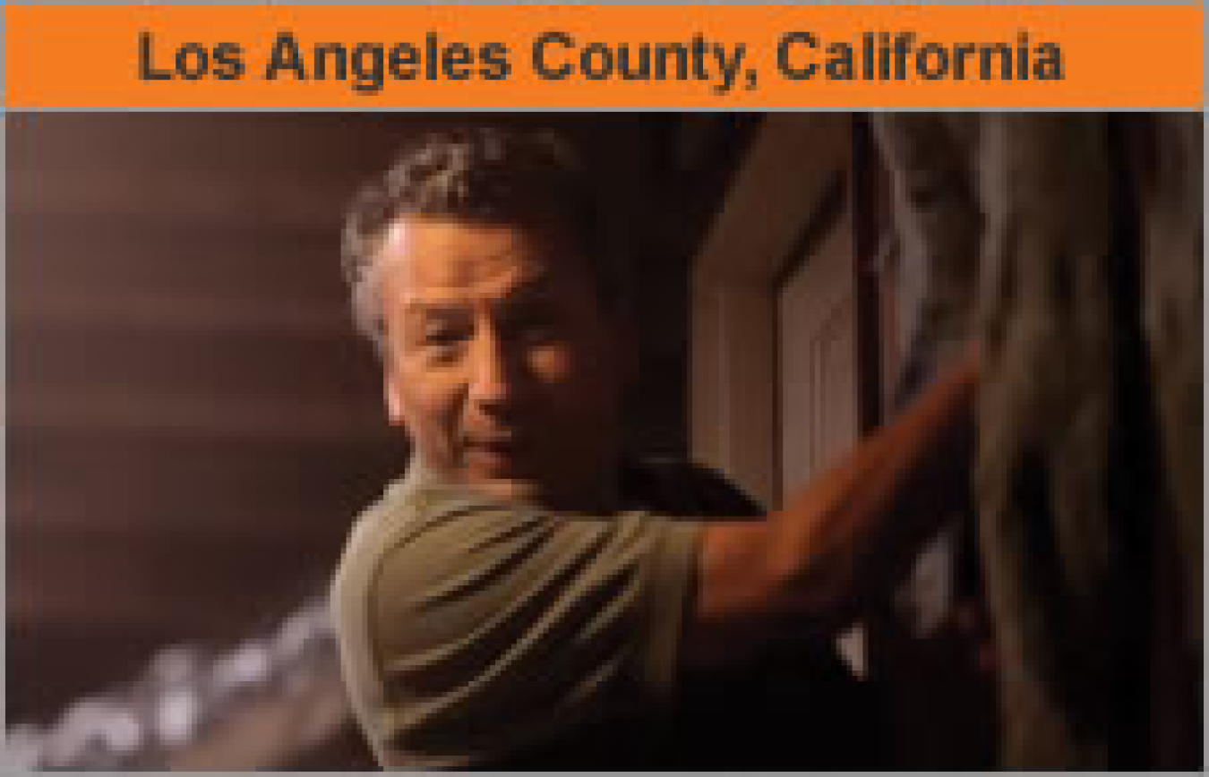 A man working inside a house, facing the camera, with the words "Los Angeles County, California."