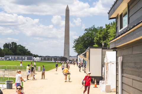 People walking on the National Mall in Washington, D.C., next to prototype buildings.